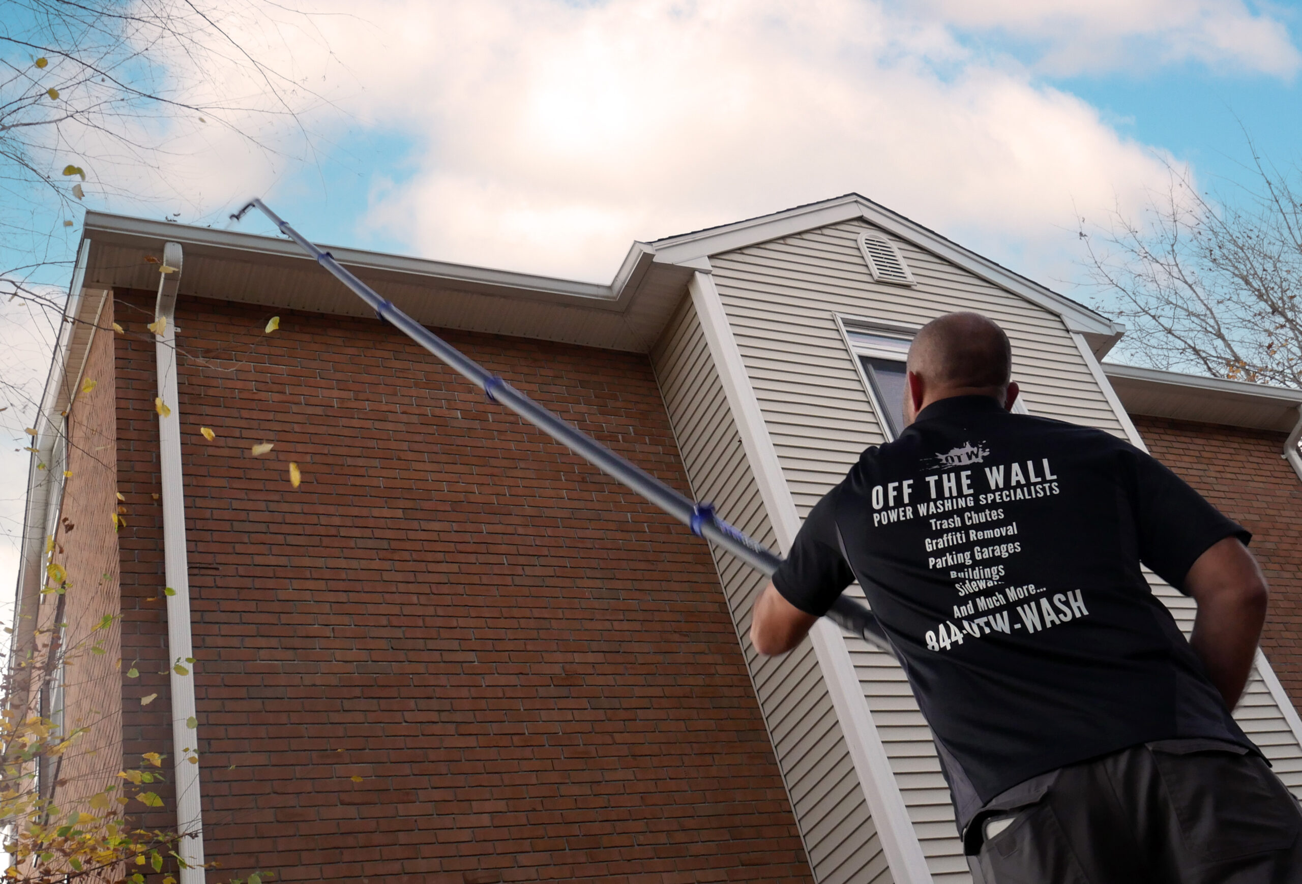 photo from a low angle of an OFF THE WALL team member cleaning a gutter