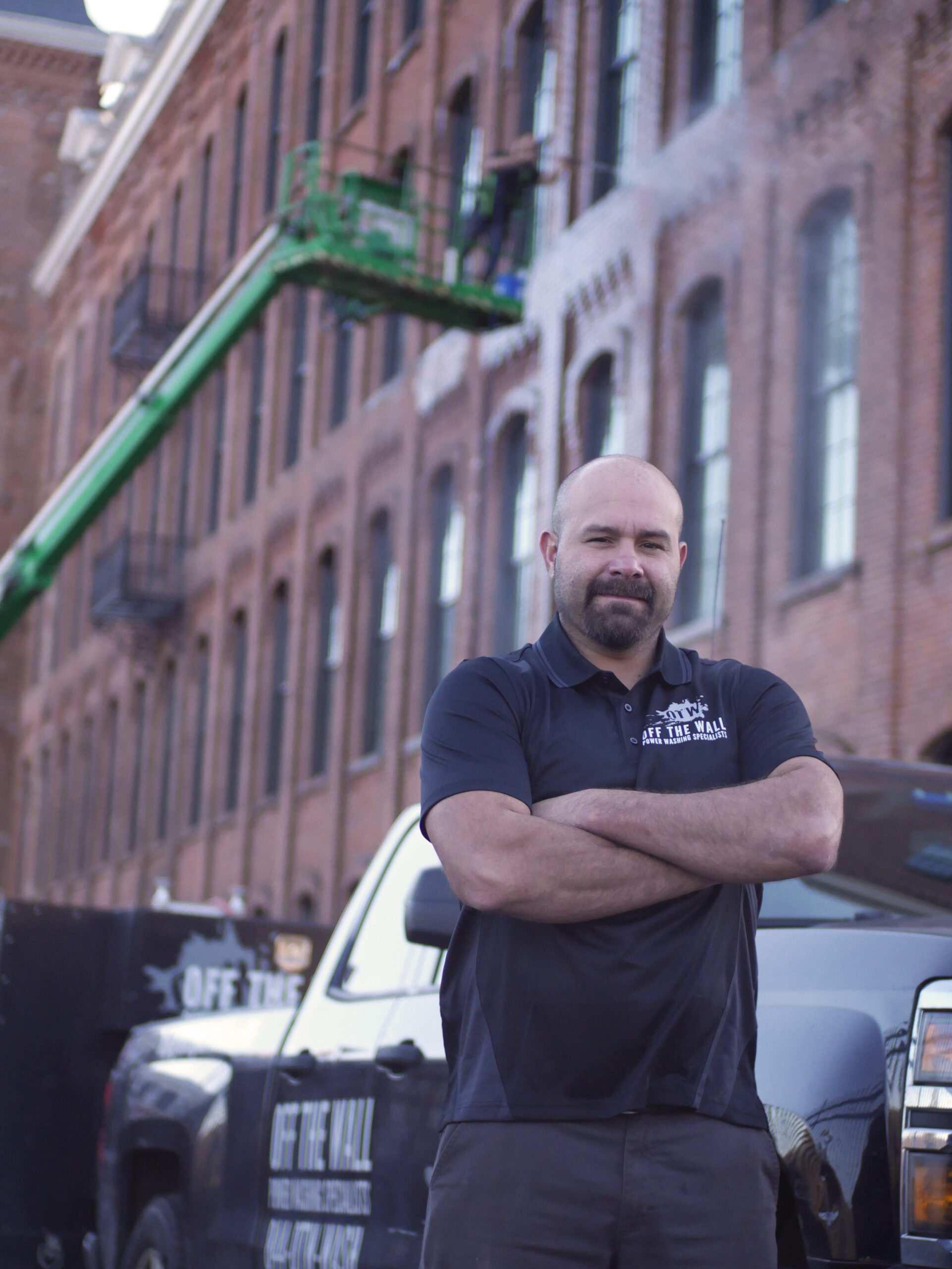 photo of Joe Prue, owner of OFF THE WALL Power Washing posing in front of his team as they clean a building.