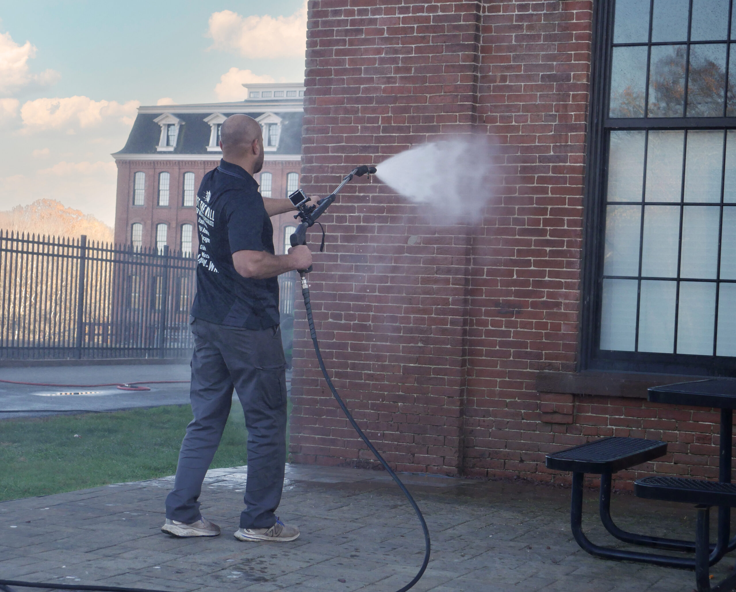 photo of an OFF THE WALL team member power washing the exterior of a brick building