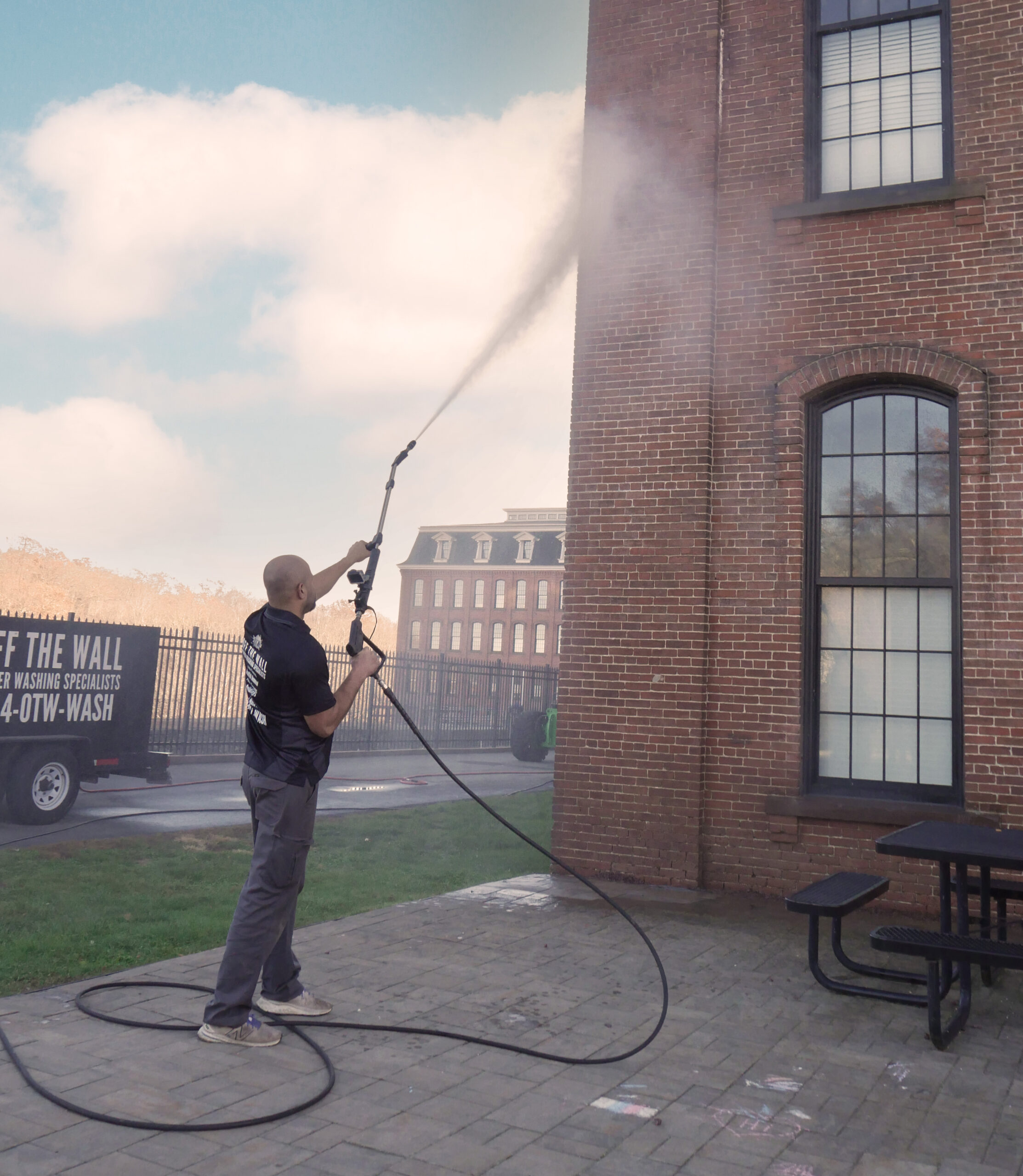 photo of an OFF THE WALL team member power washing a brick building