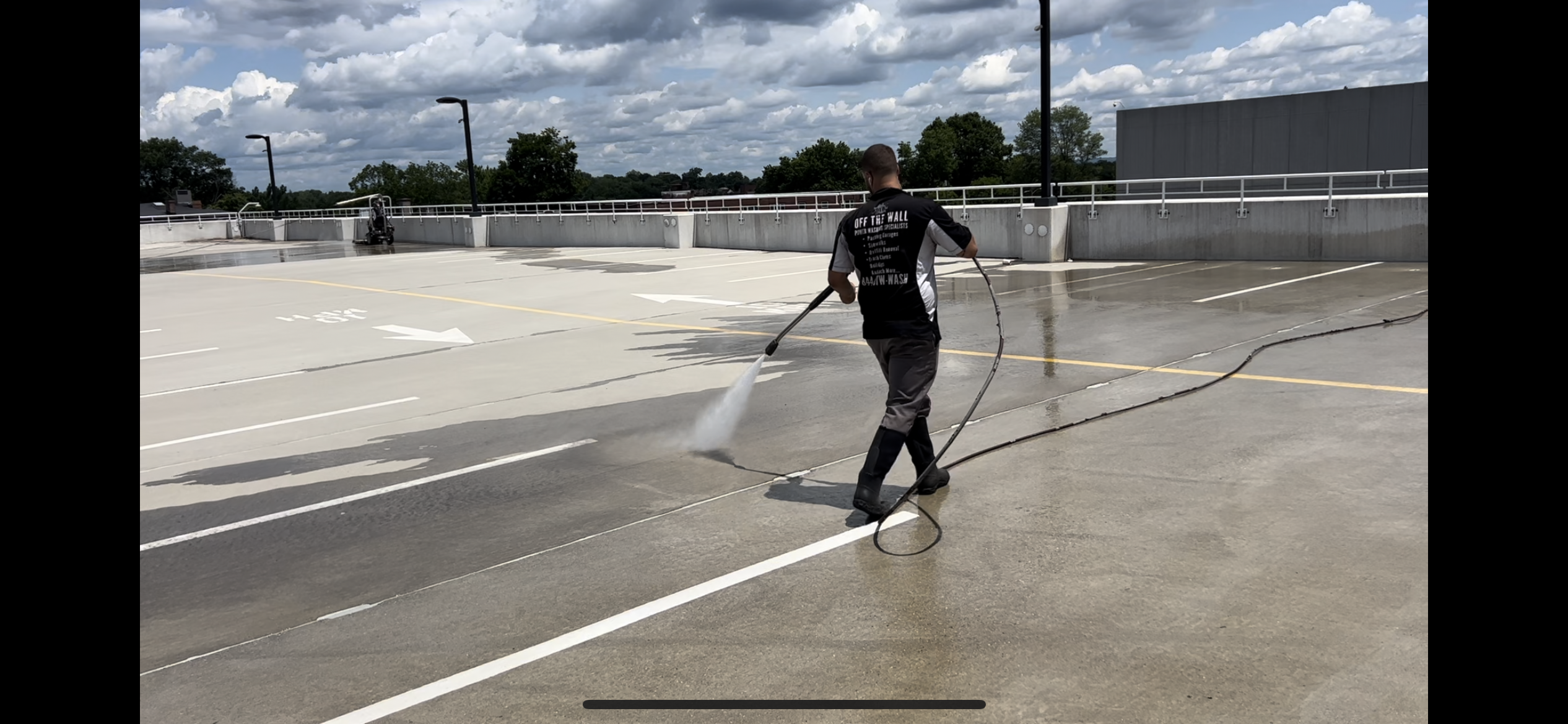 photo of an OFF THE WALL team member power washing a parking lot